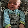 Braxton is registered to the contest to win money with this photo: baby, smiling, infant, onesie, striped_clothing, dinosaur_print, cushion, seat, hand, cozy, indoor, child, cute, portrait, young, comfortable, fabric, pattern, resting, happy