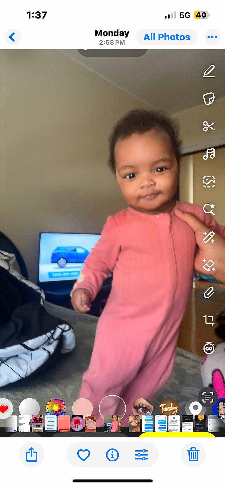 Aasheeda is registered to the contest to win money with this photo: toddler, child, baby, pink_onesie, indoor, person, hand, television, blue_car, furniture, blanket, floor, wall, room, smile, curly_hair, standing, home, cozy, casual