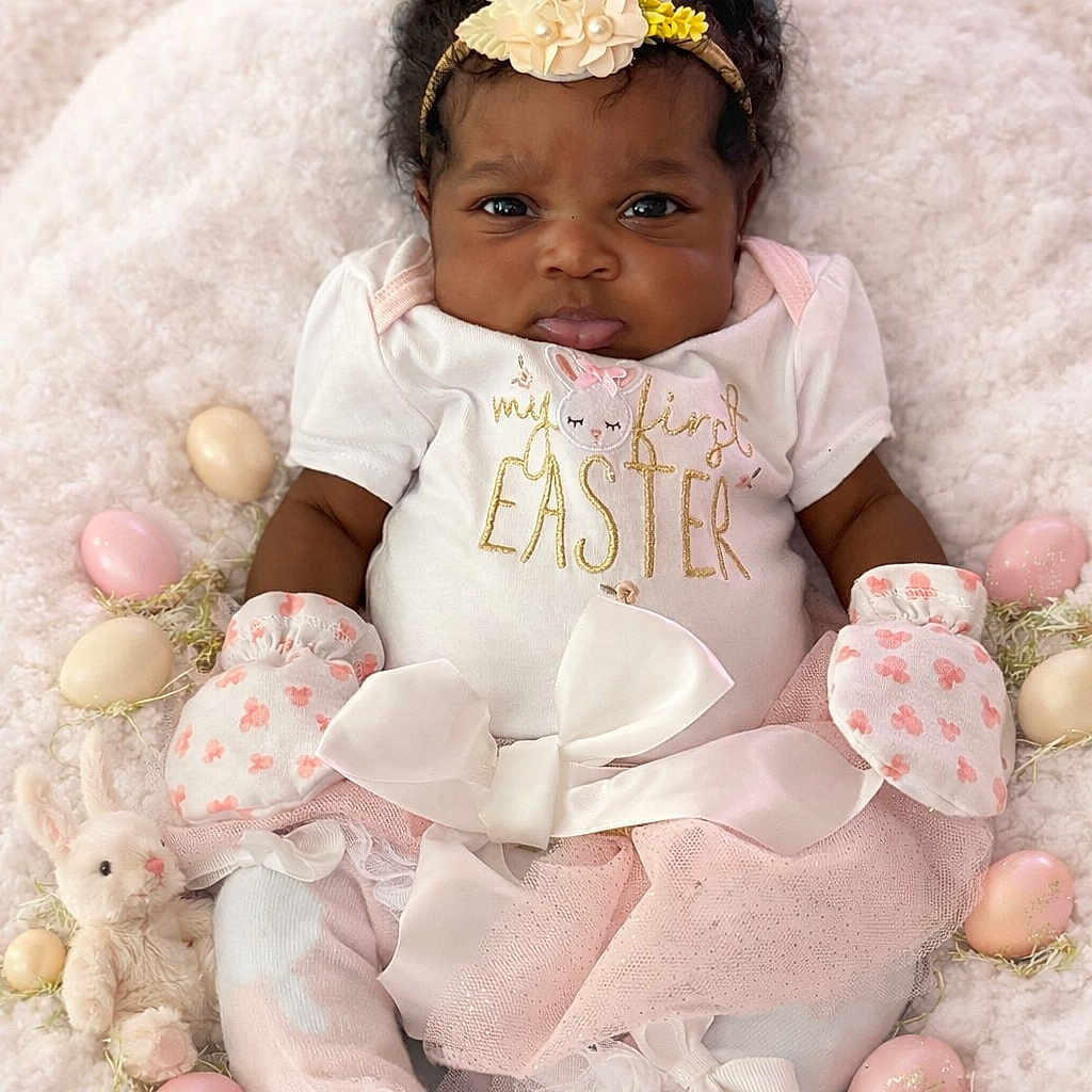 Leilani is registered to the contest to win money with this photo: baby, infant, easter, bunny_ears, mittens, plush_toy, decorative_eggs, soft_blanket, pink, white, flower_headband, tutu_skirt, cute, holiday, celebration, portrait, indoors, smiling, child, festive
