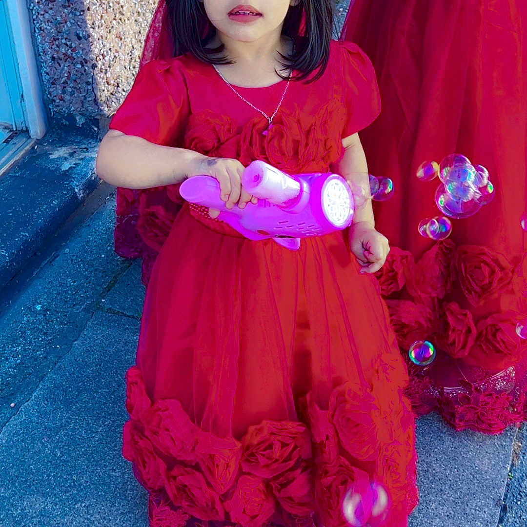 Aima joined the competition — help win amazing prizes! bubble_gun, bubbles, celebration, child, dress, face, flower_details, friends, girl, hand, happy, outdoor, party, person, playing, red_dress, sidewalk, sunlight, tiara, toy