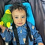 toddler, child, car_seat, plush_toy, parrot_toy, curly_hair, blue_onesie, safety_harness, indoor, smiling, face, person, cute, baby, seatbelt, holding, toy, infant, young_child, portrait