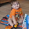 Jase joined the competition — help win amazing prizes! toddler, child, indoor, floor, orange_shirt, toy_car, play_mat, smile, shorts, brown_hair, monkey_print, bag, wooden_floor, furniture, sitting, happy, cute, play, young_child, person