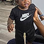 Kays a rejoint le concours — aidez-le/la à gagner de superbes lots ! black_clothing, bracelet, casual, chair, child, curly_hair, expression, flooring, footwear, hand, holding, indoor, nike, pacifier, person, sneakers, standing, striped_pants, toddler, toy
