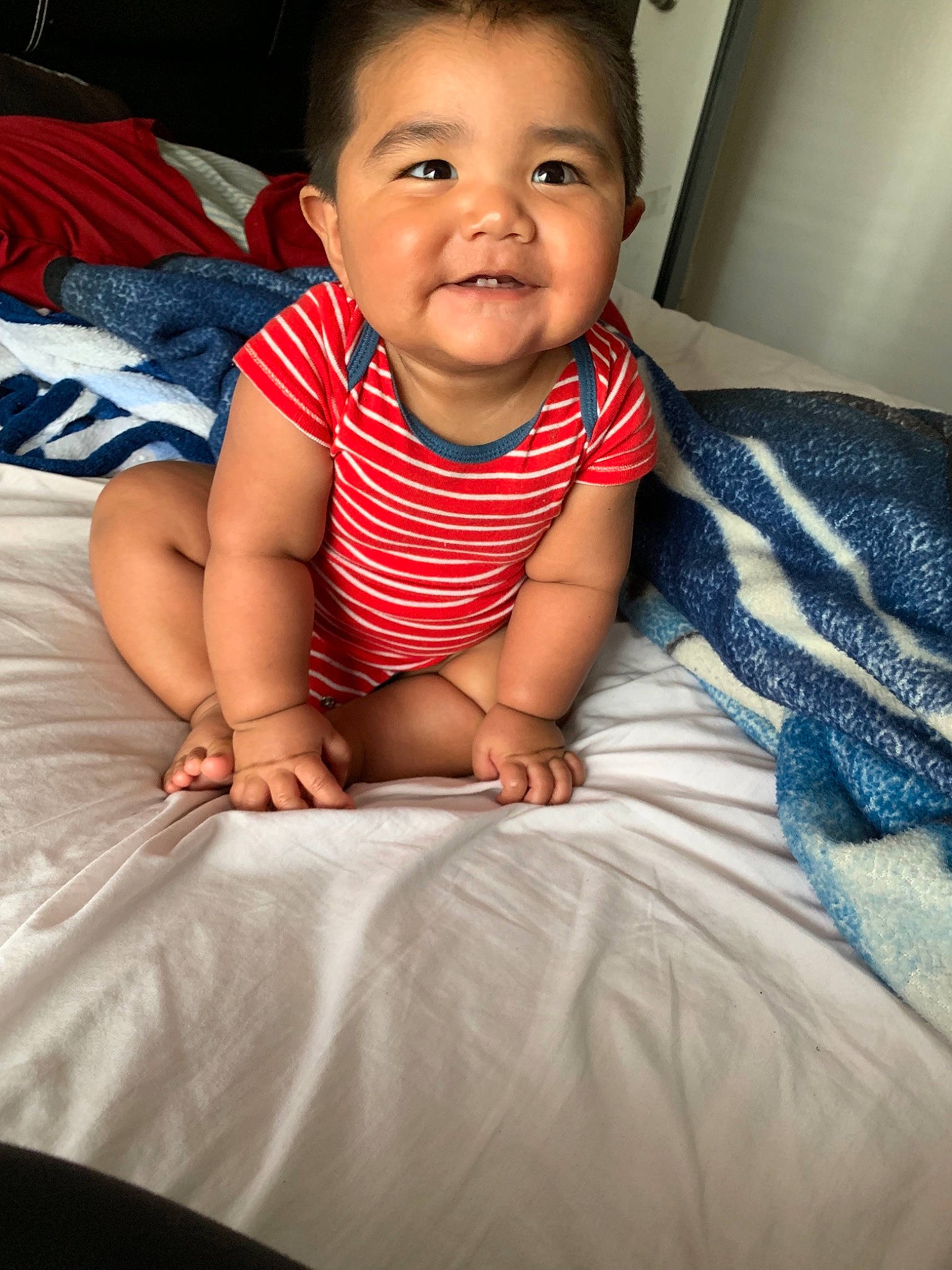 Luis is registered to the contest to win money with this photo: arm, baby, beauty, cheek, child, chin, electronic_device, eye, face, facial_expression, happy, head, leg, lip, mouth, nose, person, sitting, skin, smile