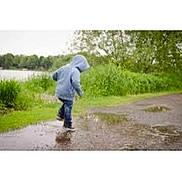 Kingston is registered to the contest to win money with this photo: child, hoodie, puddle, rainy_day, outdoor, grass, trees, water, splashing, jeans, nature, play, casual_clothing, walking, park, fun, weather, greenery, person, daytime