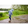 child, hoodie, puddle, rainy_day, outdoor, grass, trees, water, splashing, jeans, nature, play, casual_clothing, walking, park, fun, weather, greenery, person, daytime