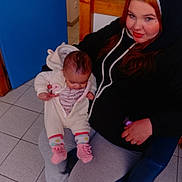 Mélodie a rejoint le concours — aidez-le/la à gagner de superbes lots ! baby, baby_clothes, casual, chair, child, clothing, face, floor, footwear, hair, holding, hoodie, indoor, pacifier, person, relaxed, sitting, socks, tile, woman