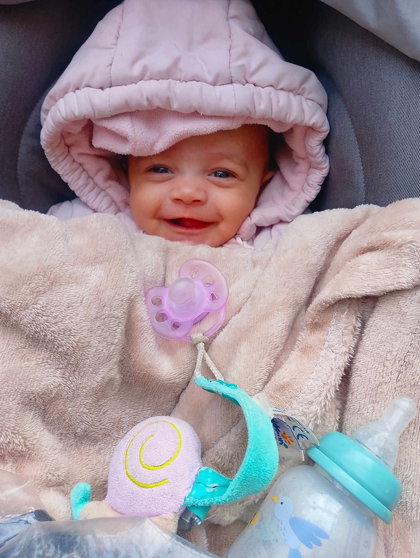 Mélodie a rejoint le concours — aidez-le/la à gagner de superbes lots ! baby, smiling, hooded_jacket, blanket, pacifier, baby_bottle, toy, cozy, infant, cute, child, wrapped, pink, beige, soft, warm, indoors, face, happy, comfort