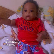 Sincere is registered to the contest to win money with this photo: baby, child, infant, red_shirt, colorful_pants, blanket, giraffe_pattern, face, eyes, curious, indoors, lying_down, person, cute, young_child, home, cozy, sleepwear, toddler, text_overlay