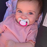 Isabella is registered to the contest to win money with this photo: baby, pacifier, pink_clothing, blanket, car_seat, face, infant, closeup, child, cute, portrait, smiling, skin, hand, eyelashes, young_child, indoors, person, comfort, soft_lighting