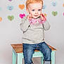 Theodore is registered to the contest to win money with this photo: background_hearts, blue_eyes, casual_clothing, child, cute, happy, heart_shaped_glasses, indoor, jeans, light_background, pastel_colors, playful, portrait, short_hair, small_furniture, smile, stool, studio_photo, toddler, white_shoes