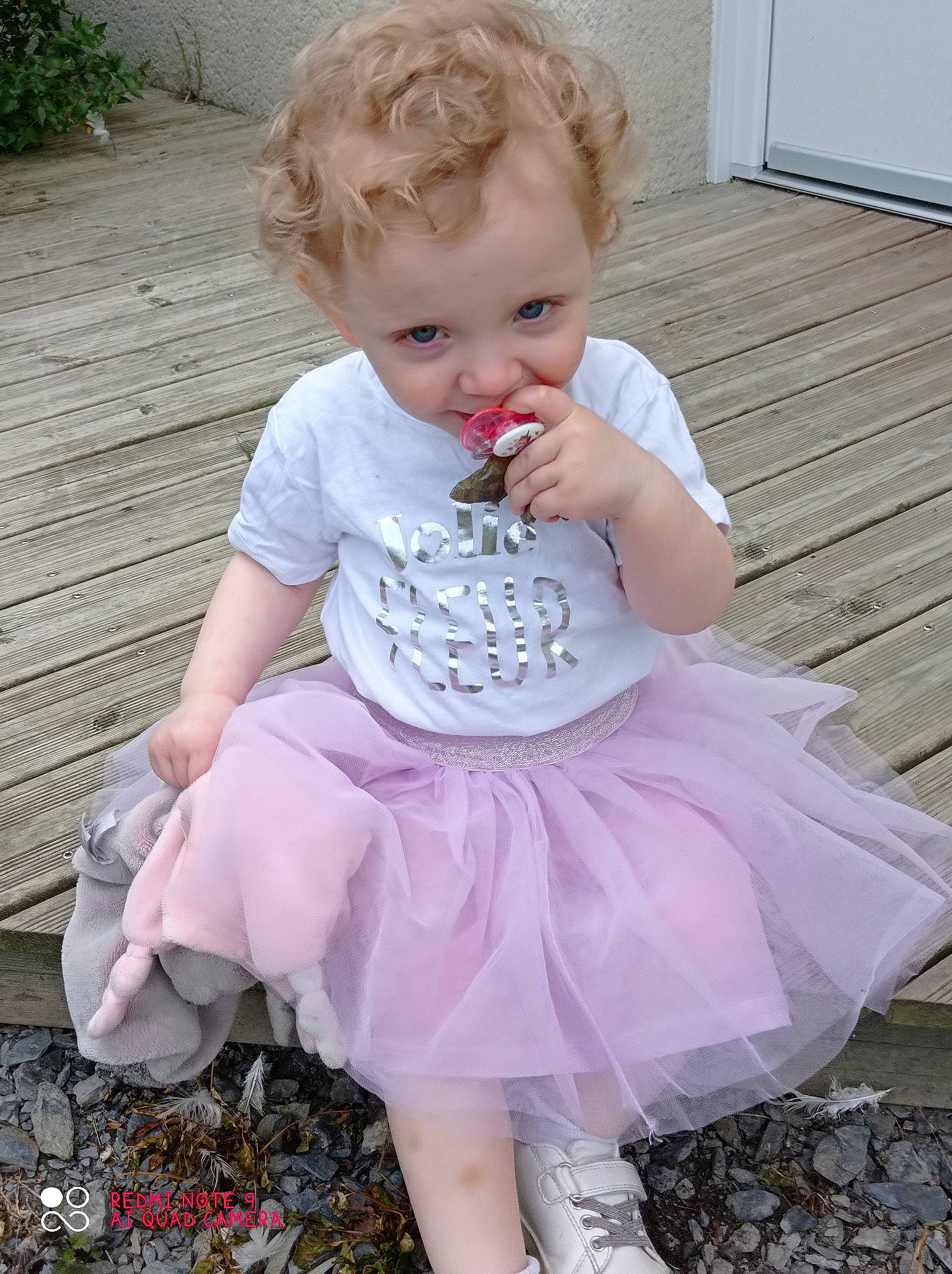 Hope participe au concours pour gagner de l'argent avec cette photo : baby, baby_products, baby_toddler_clothing, blond, child, embellishment, face, fun, grass, happy, magenta, pattern, person, pink, plant, purple, ruffle, sitting, sleeve, summer