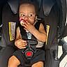 baby, pacifier, stroller, child, infant, harness, black, clothing, seat, curious, hands, legs, indoors, light, sitting, person, cute, young, car_seat, safety