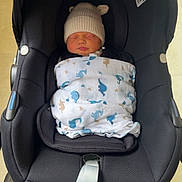 Albie is registered to the contest to win money with this photo: baby, newborn, car_seat, blanket, hat, sleeping, infant, child, indoor, black, fabric, wheel, floor, cute, bundle, resting, toddler, comfort, soft, transport