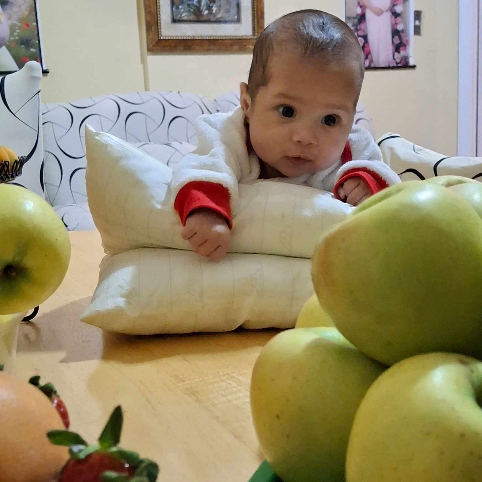 Candida is registered to the contest to win money with this photo: apple, baby, child, couch, curious, decor, face, food, fruit, healthy, home, indoor, infant, person, pillow, portrait, soft_lighting, strawberry, table, wall_art