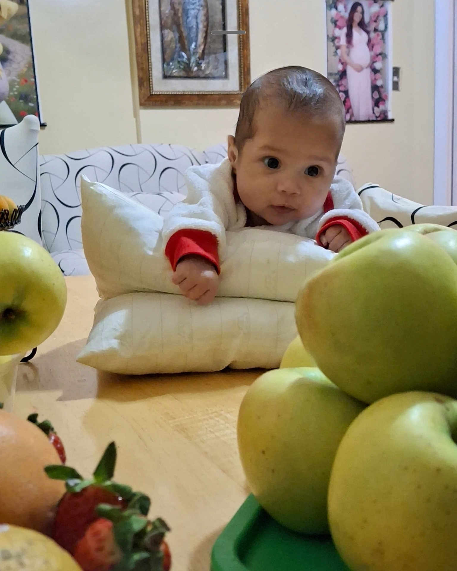 Candida is registered to the contest to win money with this photo: baby, infant, fruit, apple, strawberry, table, pillow, indoor, face, curious, food, healthy, home, decor, portrait, child, soft_lighting, couch, wall_art, person