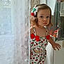 toddler, child, curtain, indoor, face, hair_accessory, red_bow, cherry_pattern, clothing, person, cute, serious_expression, window, white_curtain, light, home, skin, short_hair, standing, baby