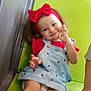 Cataleya a rejoint le concours — aidez-le/la à gagner de superbes lots ! toddler, child, smile, red_headband, bow, denim_dress, green_seat, hand_gesture, sitting, indoor, person, cute, happy, legs, diaper, casual_clothing, playful, adult_hand, portrait, face