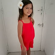 Giulina a rejoint le concours — aidez-le/la à gagner de superbes lots ! child, girl, smiling, red_clothing, flower, hair_accessory, standing, indoor, door, white_wall, floor, portrait, happy, person, fashion, cute, youth, casual, posing, young