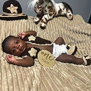 Dakarai is registered to the contest to win money with this photo: baby, infant, one_month, crocheted_clothing, blanket, plush_toy, horse_toy, hat, booties, brown_skin, lying_down, portrait, cute, milestone, baby_clothes, indoor, soft_texture, decor, child, newborn