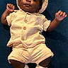 baby, child, infant, clothing, hat, socks, cute, smiling, face, portrait, lying_down, beige_outfit, blue_background, happy, small_hands, buttoned_shirt, shorts, indoor, person, young