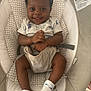 baby, baby_seat, child, clothing, comfort, cushion, cute, face, hands, happy, headband, indoors, infant, legs, pattern, person, seatbelt, skin, smiling, socks