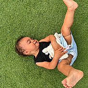Louwene participe au concours pour gagner de l'argent avec cette photo : barefoot, black_top, carefree, child, cute, grass, happy, infant, lying_down, nature, outdoor, person, playing, playtime, plush_toy, shorts, smiling, summer, toddler, toy