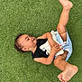 barefoot, black_top, carefree, child, cute, grass, happy, infant, lying_down, nature, outdoor, person, playing, playtime, plush_toy, shorts, smiling, summer, toddler, toy
