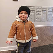 Jaxson is registered to the contest to win money with this photo: child, toddler, jacket, beanie, hat, sneakers, mailboxes, hallway, flooring, mat, indoor, person, clothing, cute, standing, smile, winter, cozy, young, casual