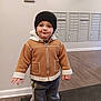 child, toddler, jacket, beanie, hat, sneakers, mailboxes, hallway, flooring, mat, indoor, person, clothing, cute, standing, smile, winter, cozy, young, casual