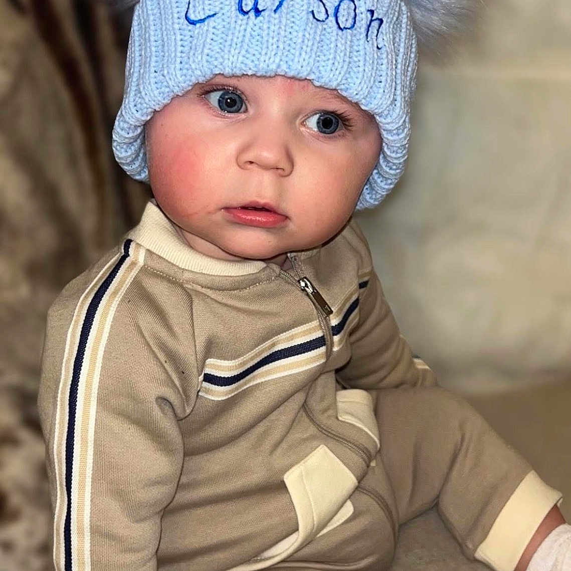 Carson joined the competition — help win amazing prizes! baby, beanie, blonde, bonnet, cap, clothing, face, hair, happy, hat, head, knitwear, pants, person, photography, portrait, sitting, sleeve, smile