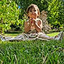 child, toddler, grass, park, outdoor, trees, sunlight, dress, curly_hair, shoes, nature, greenery, blue_sky, playful, cute, summer, daylight, sitting, person, young_child