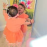 toddler, child, mirror, reflection, orange_dress, headband, balloons, carpet, room, celebration, decoration, smile, bracelet, curtain, window, full_length_mirror, indoor, happy, party, wall
