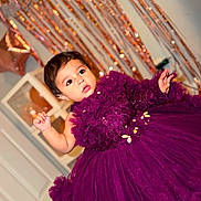 Miral joined the competition — help win amazing prizes! baby, purple_dress, tulle, flower_details, curly_hair, face, celebration, party_decor, balloons, streamers, indoor, child, cute, portrait, festive, smiling, hand_raised, eyes, dress, adorable
