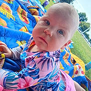 Nevaeh is registered to the contest to win money with this photo: baby, child, outdoor, grass, blanket, colorful, swimsuit, floral, sunny, daylight, portrait, cute, infant, person, nature, summer, playtime, relaxation, expression, park