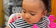 Inaya a rejoint le concours — aidez-le/la à gagner de superbes lots ! baby_walker, black, child, closeup, curly_hair, cute, face, focus, indoor, infant, person, pink, pink_bows, playing, seat, striped_clothing, toddler, toy, white, young_child