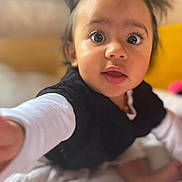 Inaya a rejoint le concours — aidez-le/la à gagner de superbes lots ! baby, bed, black_vest, blanket, child, closeup, clothing, curious, cute, expression, eyes, face, hair, hand, indoor, portrait, skin, toddler, white_shirt, young