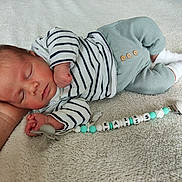 Kaiis a rejoint le concours — aidez-le/la à gagner de superbes lots ! baby, newborn, sleeping, striped_clothing, pajamas, pacifier, hand, blanket, soft_texture, infant, cute, resting, peaceful, person, lying_down, white_socks, toy, closeup, indoor, portrait