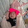 baby, infant, blanket, bow, headband, smile, sleeping, cushion, toy, pink, black_clothing, earrings, soft_texture, indoor, cozy, child, cute, resting, home, comfort