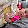 Emmeline is registered to the contest to win money with this photo: baby, blanket, pink_clothing, infant, face, hand, cushion, soft_texture, lying_down, portrait, cute, newborn, skin, expression, indoor, comfort, resting, child, young, sleepwear