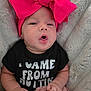 baby, infant, headband, pink_bow, black_onesie, text_on_clothing, blanket, soft_texture, cute, expression, face, hands, lying_down, child, adorable, cozy, indoors, newborn, skin, clothing
