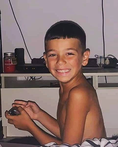 Soann a rejoint le concours — aidez-le/la à gagner de superbes lots ! barechested, black_hair, chest, elbow, eyebrow, eyelash, finger, flash_photography, gesture, hairstyle, hand, happy, joy, muscle, person, room, sitting, smile, thumb, toddler