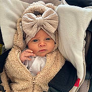 Romy participe au concours pour gagner de l'argent avec cette photo : baby, infant, child, face, headband, bow, clothing, coat, zipper, car_seat, cushion, blanket, fur, soft, cute, portrait, indoors, person, young, bundle