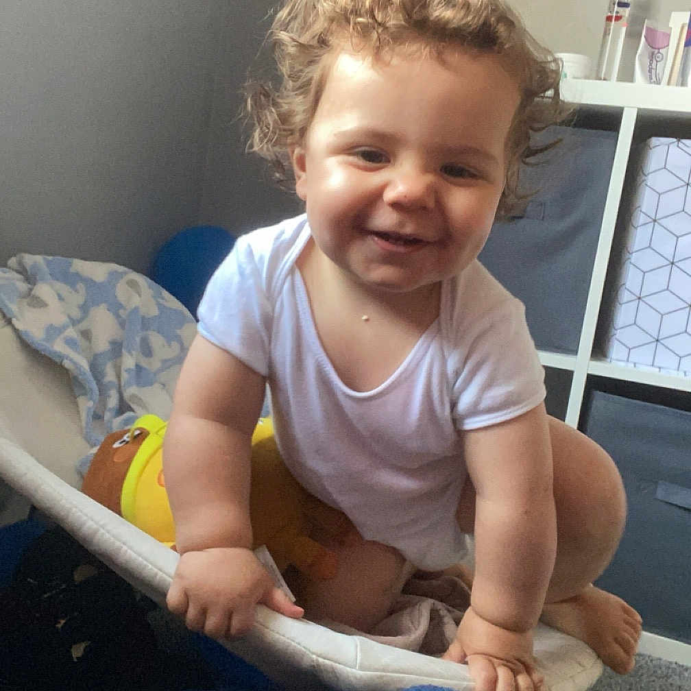 Kai is registered to the contest to win money with this photo: baby, bed, clothing, crib, face, furniture, happy, head, indoors, infantbed, jeans, laughing, pants, person, photography, portrait, shorts, sitting, smile, t_shirt
