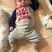 Liam joined the competition — help win amazing prizes! baby, infant, smiling, clothing, shirt, bed, bedding, pillow, pacifier, blanket, sock, striped_pants, person, cute, happy, lying_down, indoors, child, newborn, face