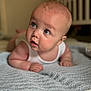 baby, infant, blue_eyes, lying_down, blanket, crib, soft_texture, curious, indoors, nursery, child, person, tummy_time, cute, skin, expression, head, face, white_clothing, closeup