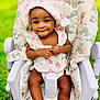 Khwezi is registered to the contest to win money with this photo: baby, infant, toddler, high_chair, strawberry_hat, smile, eyes, hands, legs, onesie, seat, patterned_fabric, outdoor, grass, portrait, cute, happy, child, playful, nursery_prints