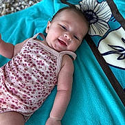 Alix participe au concours pour gagner de l'argent avec cette photo : baby, infant, smiling, towel, floral_onesie, cute, happy, skin, arm, hand, face, head, laying_down, pattern, textile, blue_towel, background, closeup, portrait, child