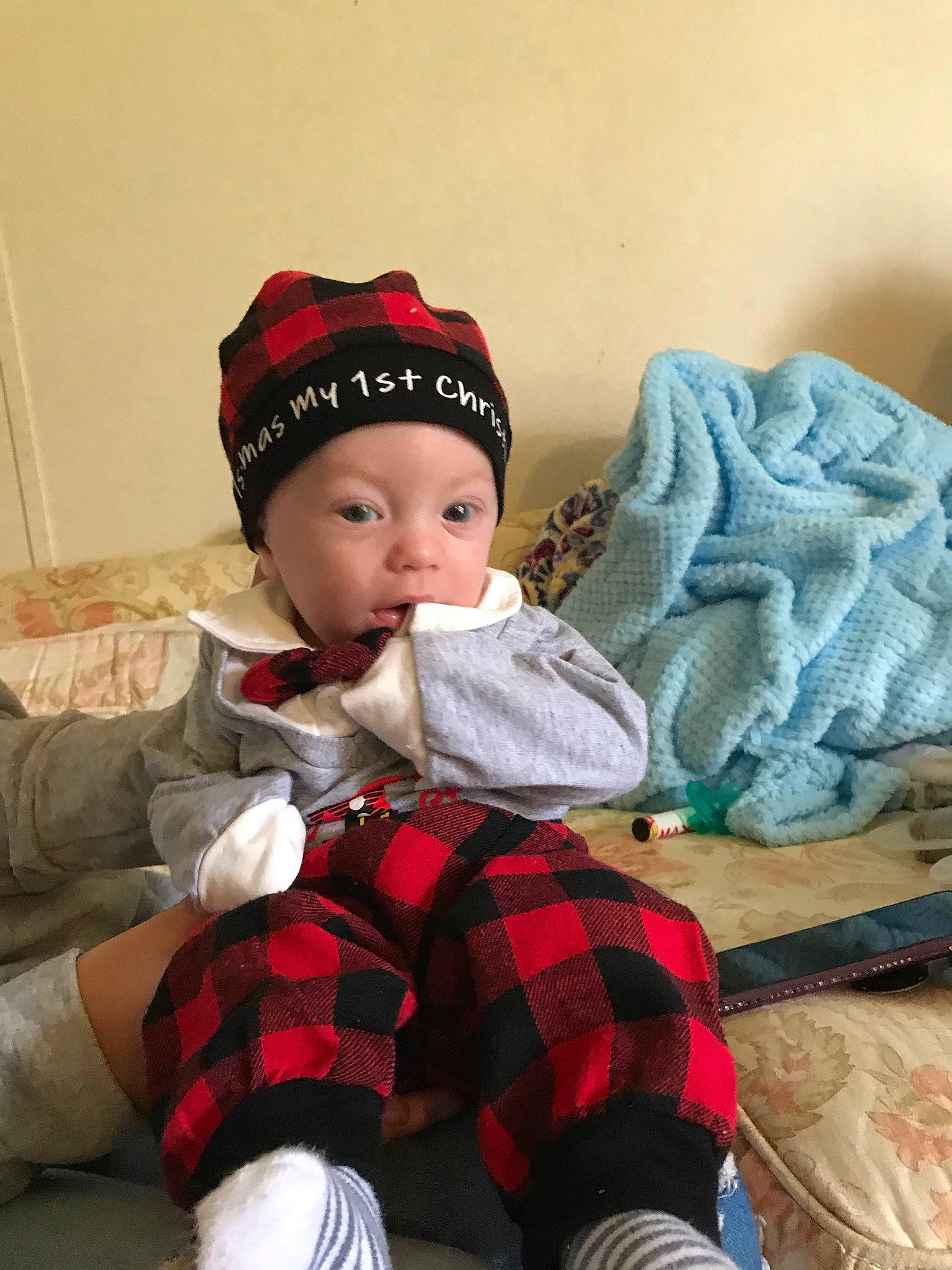 Oaklee is registered to the contest to win money with this photo: baby, baby_toddler_clothing, cap, child, clothing, comfort, costume_hat, headgear, headwear, holiday, lap, leg, mammal, person, plaid, sitting, sleeve, sock, tartan, textile