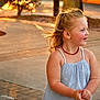 child, girl, smiling, sunset, outdoor, sidewalk, blonde_hair, earrings, necklace, blue_dress, happy, portrait, young, casual_clothing, daylight, warm_light, motion, cute, skin, person